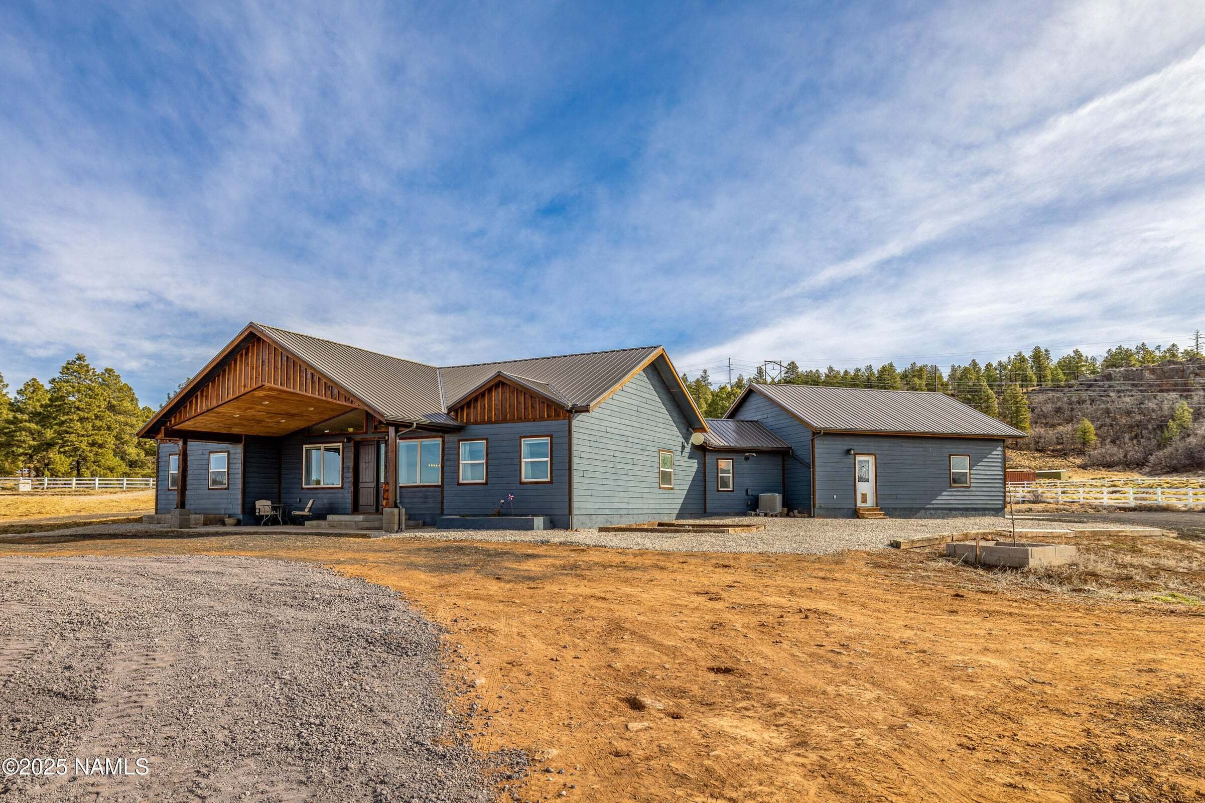 The front of a blue house with dirt driveway